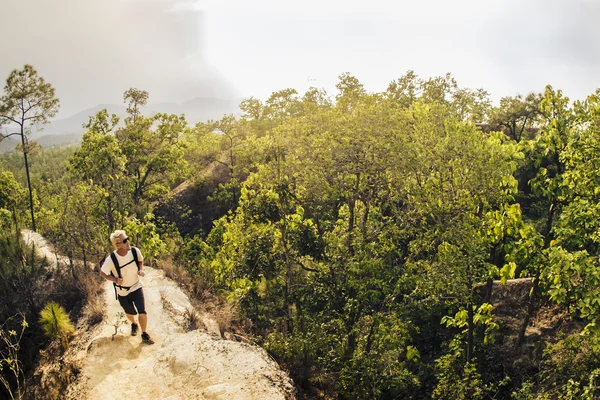 Чоловік ходить по горах у білій сорочці та рюкзаку — стокове фото