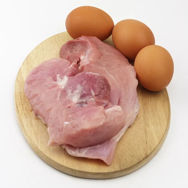 Jamón de cerdo crudo y huevos en tabla de cortar de madera sobre fondo blanco Fotos De Stock Sin Royalties Gratis