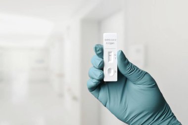 Eldivenli el COVID-19 için hızlı bir test cihazı tutuyor..