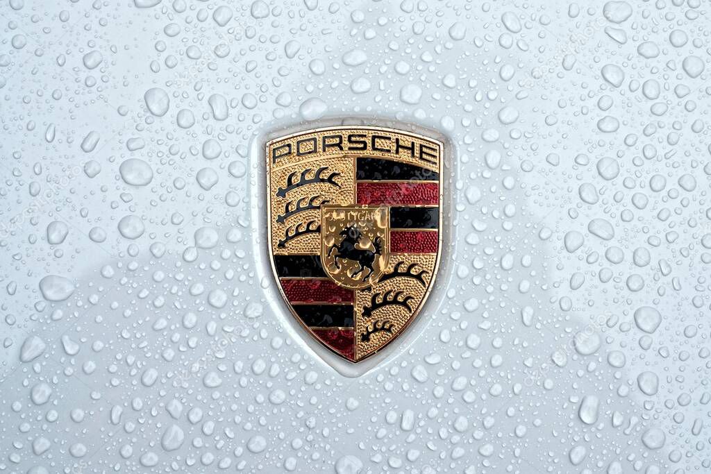 Neu-Ulm, Bavaria, Germany - May 21, 2021: Close up of a Porsche car logo on metallic surface with rain drops.