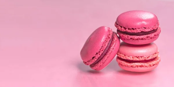 Multi-colored macaroons on a pink background. Panoramic image with copy space.