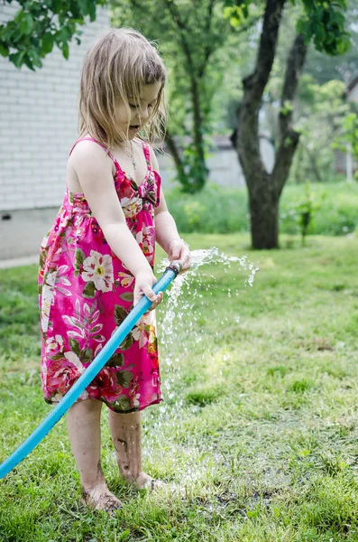 Girl plays with water hose — Stock Photo, Image