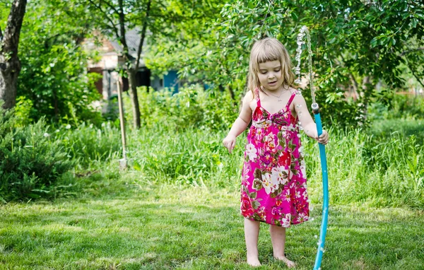 Girl plays with water hose — Stock Photo, Image