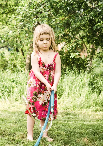 Girl plays with water hose — Stock Photo, Image