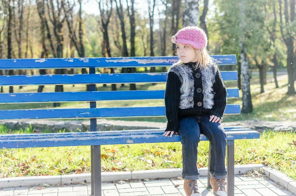 Petite fille assise sur le banc au parc d'automne — Photo