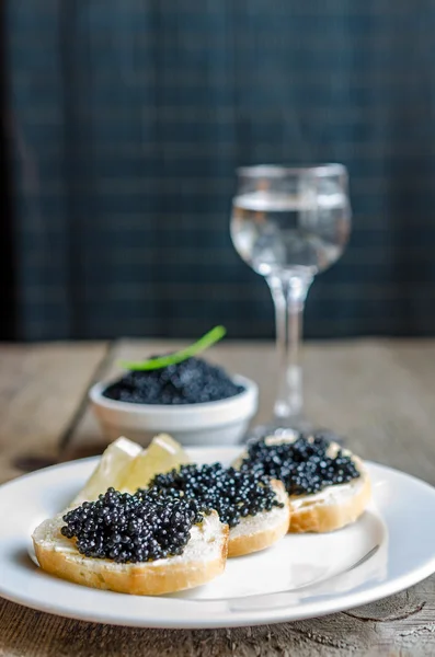 Sanduíches com caviar preto e copo de vodka — Fotografia de Stock