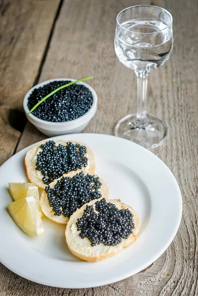 Sandwiches con caviar negro y vaso de vodka —  Fotos de Stock