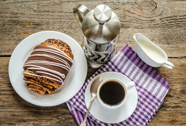 Cup of coffee and poppy bun glazed with ganache — Stock Photo, Image