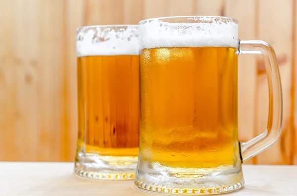 Две кружки пива на деревянном фоне — стоковое фото