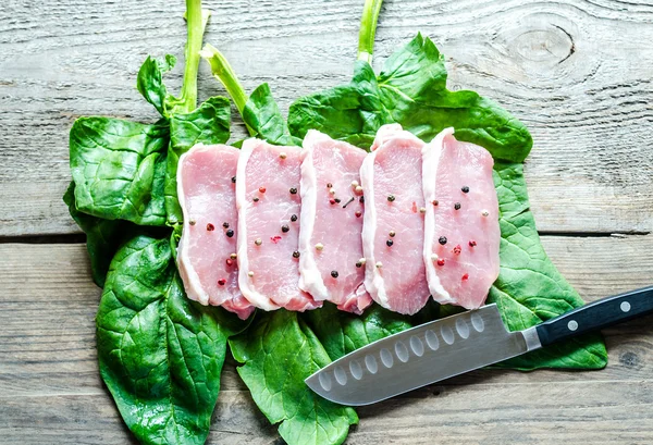 Raw meat steaks on spinach leaves — Stock Photo, Image