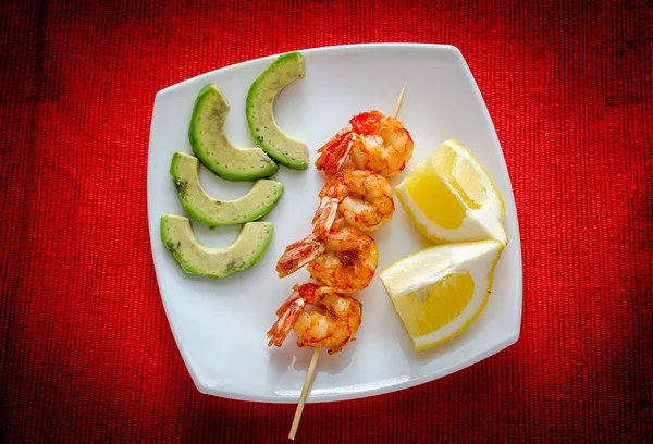 Brochetas de camarones con aguacate y rodajas de limón — Foto de Stock