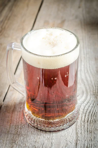 Mok met donker bier op de houten tafel — Stockfoto