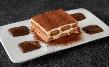 Bir porsiyon tiramisu, çikolatayla süslenmiş İtalyan tatlısı.