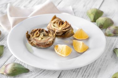 Tabağında limon olan fırında enginar.