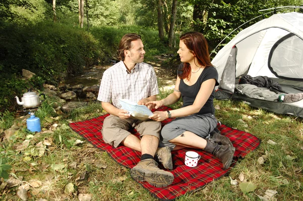 Par diskuterade vandring planer infront av ett tält - camping serie — Stockfoto