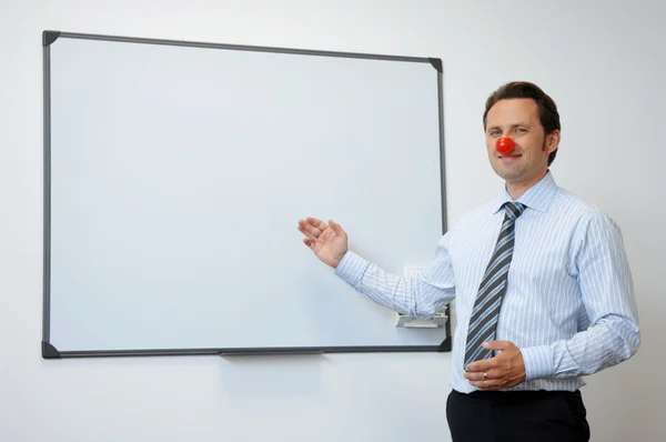 Zakelijke clown met rode neus presenteren iets op het bord — Stockfoto