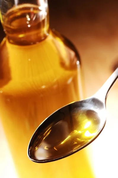 Aceite de oliva en cuchara y botella en el fondo —  Fotos de Stock