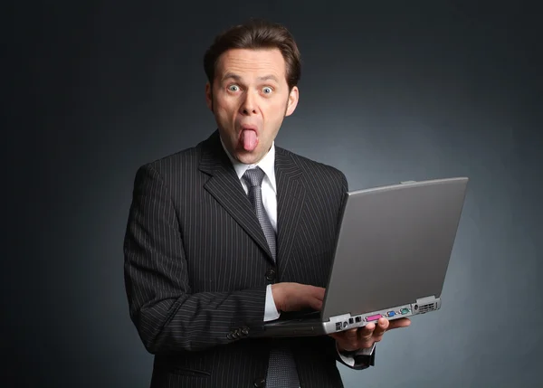 Businessman with laptop streching out his tongue — Stock Photo, Image