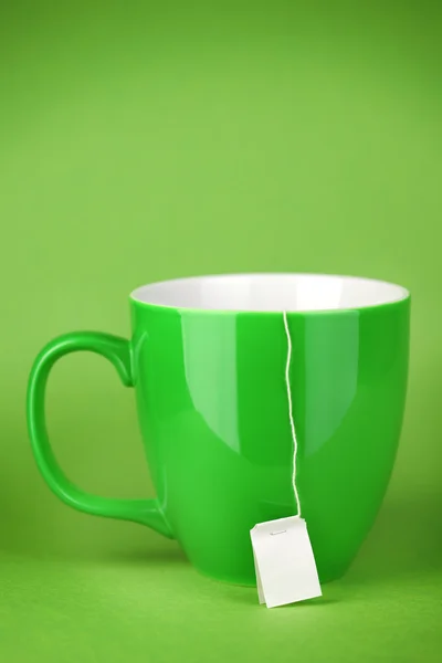 Caneca verde de chá com rótulo em branco — Fotografia de Stock