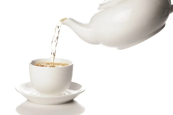 Pouring green tea from a white teapot into a mug — Stock Photo, Image