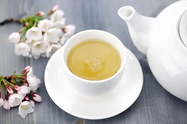Tazza di tè verde e fiori di ciliegio giapponesi Fotografia Stock