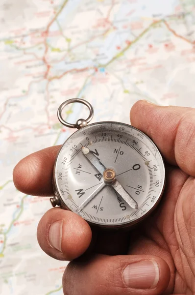 Ręka trzyma kompas, mapa z fokusem w tle — Zdjęcie stockowe