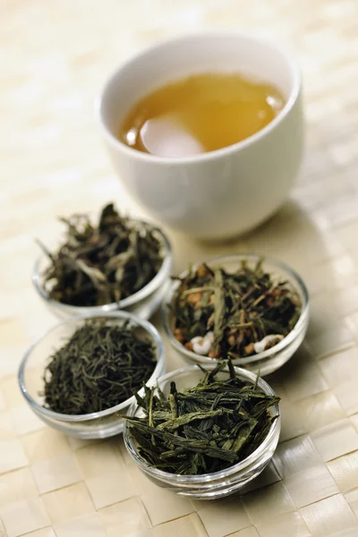 Различные сорта зеленого чая и чашки — стоковое фото