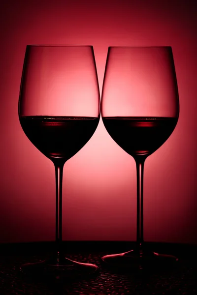 Two glasses filled with red wine against red background — Stock Photo, Image