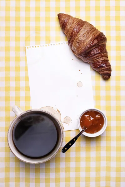 Frühstücksszene mit Kaffee, Croissant, Marmelade und leerem Papier Stockfoto
