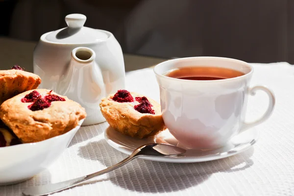 Цветочный чай с пирожными и малиной на столе — стоковое фото