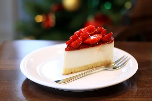 Cheesecake with strawberries on a festive New Year's table on the background of trees — Stock Photo, Image