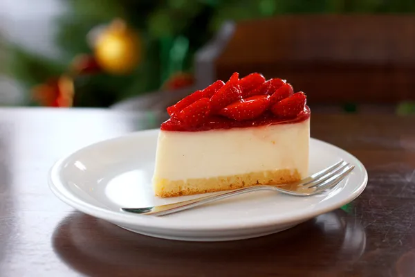 Cheesecake met aardbeien op een feestelijke new year's tabel op de achtergrond van bomen — Stockfoto