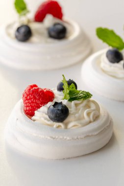 Krem şanti, ahududu, yabanmersini ve nane yaprağıyla bezeli yuvalar.