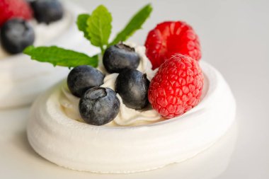 Krem şanti, ahududu, yabanmersini ve nane yaprağıyla bezeli yuvalar.