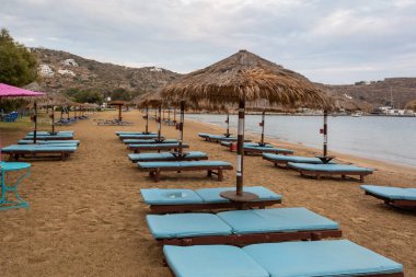 Ios Adası 'ndaki Chora' nın kumlu sahilinde şemsiyeli plaj salonları. Cyclades, Yunanistan