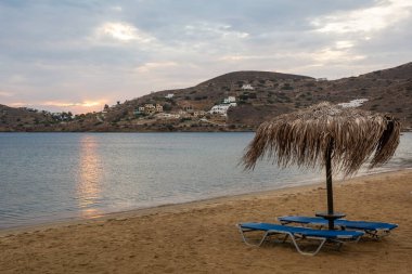 Ios Adası 'ndaki Chora' nın kumlu sahilinde güneşli şezlonglu saman şemsiyesi. Cyclades, Yunanistan