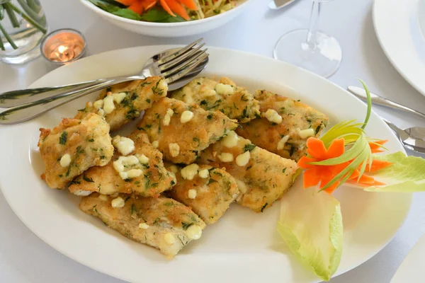 Fried cod fillets in herb crumble on a plate