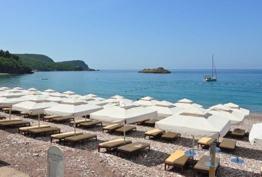 Sveti Stefan, Montenegro - June 6, 2022: Umbrellas on Sveti Stefan beach, one of the most beautiful beaches in Montenegro. Europe