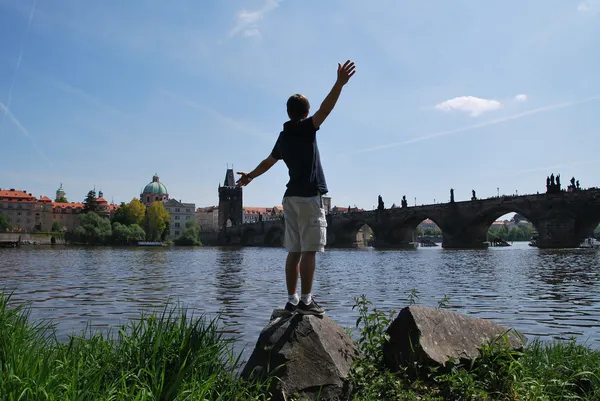 Genç bir adam kollarını Prag'da nehrin iki taraf için de dışarı uzatılmış şort — Stok fotoğraf