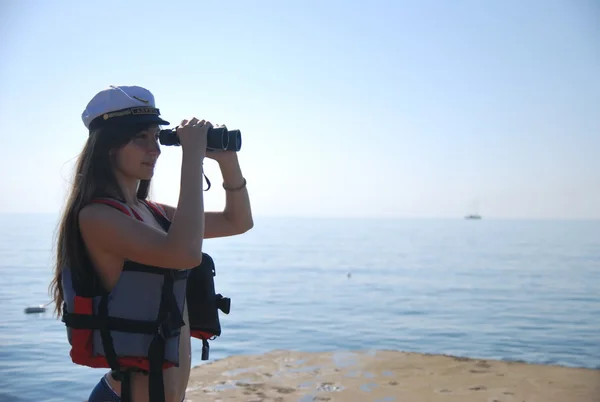 Young girl looking through binoculars into the distance on sailing ships on the Black Sea — Stock Photo, Image