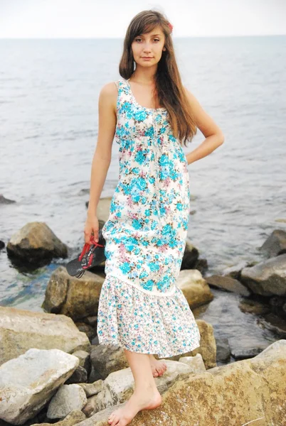 Young girl with long dark hair posing on the huge rocks by the sea — Stock Photo, Image