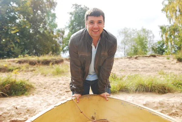 Young man holding his edge of the boat to push it away and sail — Stock Photo, Image