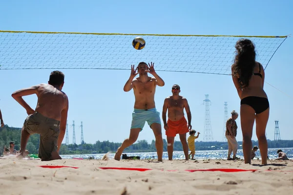 Jonge mensen spelen van beachvolleybal op het zand in de buurt van de dam water — Stockfoto