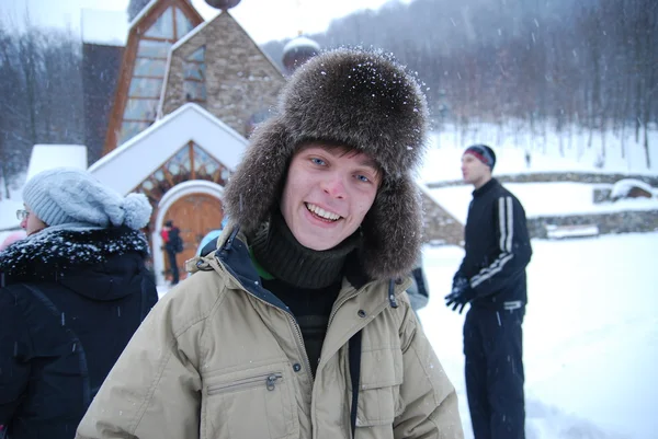 Um jovem em um boné com abas auriculares durante caminhadas de inverno . — Fotografia de Stock