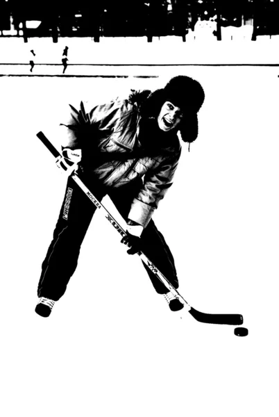 Um jovem em um boné com abas de orelha fica em uma pista de patinação com um bastão de hóquei — Fotografia de Stock