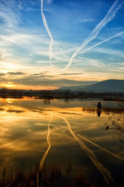 View of Iseo lake with chemtrails in the sky at sunset clipart