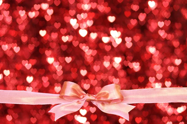 Glossy pink bow with a lot of hearts background. — Stock Photo, Image