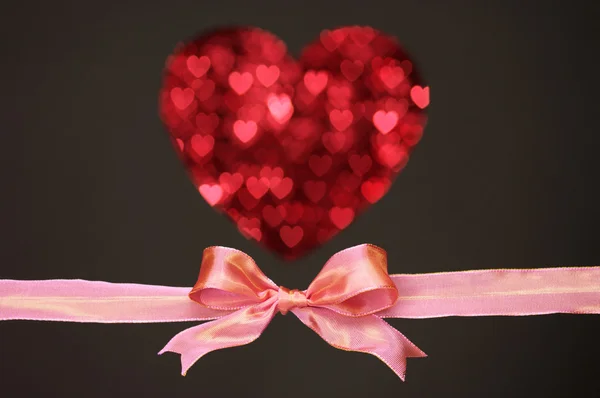 Glossy pink bow and heart shape by little heart, on black background. — Stock Photo, Image