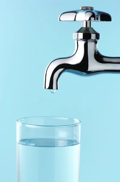 Glass of water and tap with drop. — Stock Photo, Image