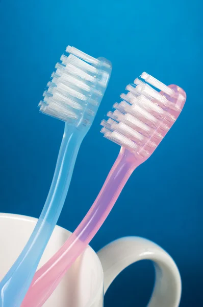 Two toothbrushes and a cup. (vertical) — Stock Photo, Image